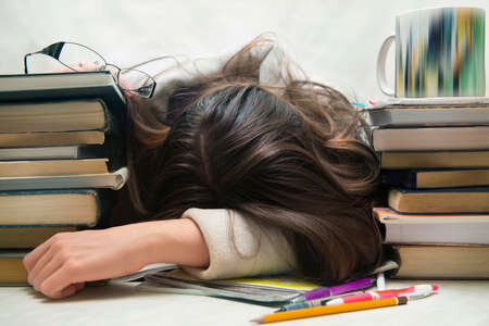 53763804 student moe van huiswerk studeren met pen in slaap op open boeken gei%cc%88soleerd 